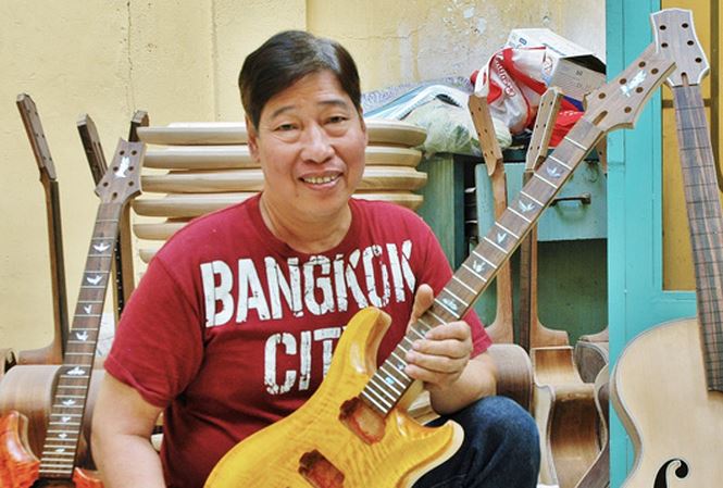 Nghệ nhân Ngọc Thức bên cây đàn ghita điện mà anh đang hoàn thiện. Ảnh: Trần Anh