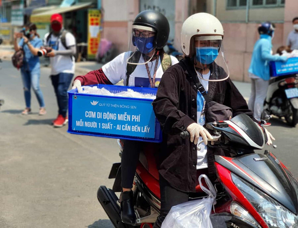 Những tình nguyện viên các quán cơm Nụ Cười đi phân phát các suất ăn cho người nghèo. Ảnh: Như Lịch