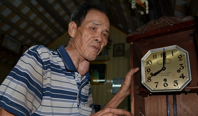 Ông Kiển “nghe” âm thanh đồng hồ bằng cảm nhận từ tay. Ảnh: Bùi An A